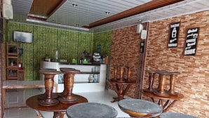 A restaurant interior with wooden tables and stools, a counter with a cash register, and a wall with a 'DRINK MORE WATER' sign.