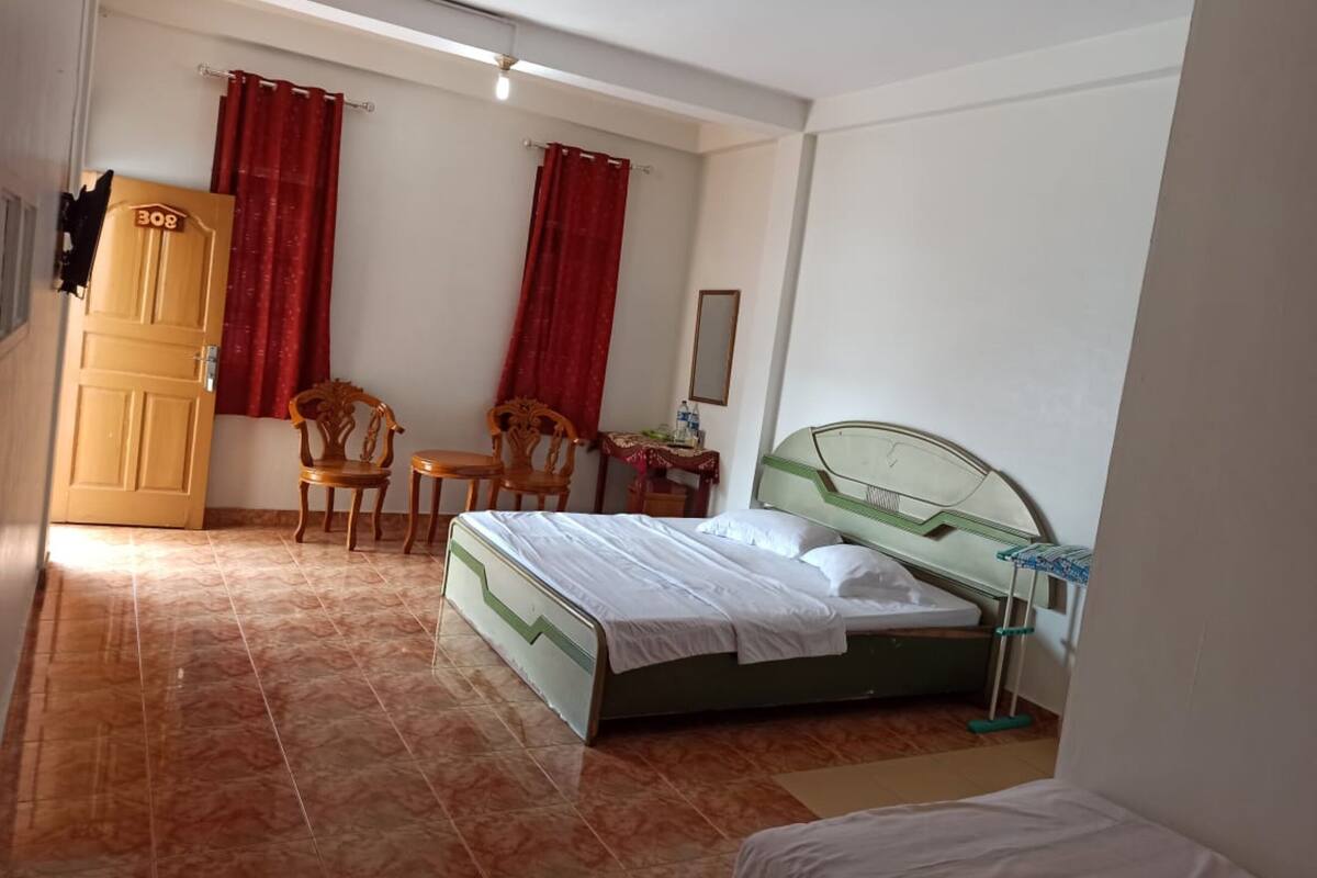 A bedroom with a bed, two chairs, a table, and a wardrobe.