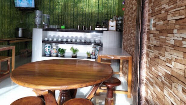 A dining area with a wooden table and chairs, a bar area with a TV, and a brick wall.
