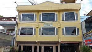 A two-story building with a sign indicating it is a hotel. There are multiple windows on the facade, and several motorcycles are parked in front.