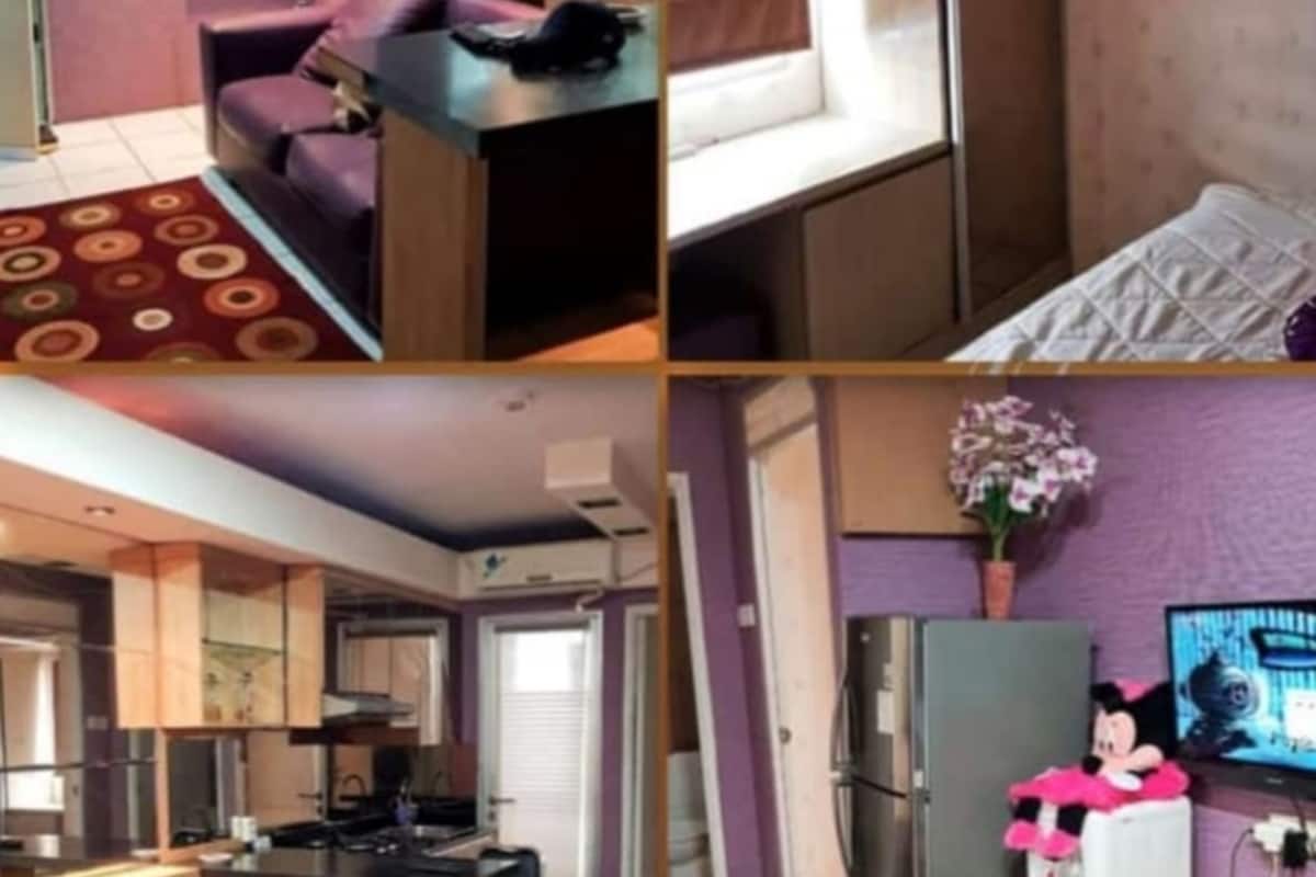 Een kamer met een paarse bank, een klein tafeltje, een spiegel en een raam met jaloezieën.