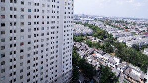A high-rise building with multiple windows and a view of a residential area with houses and greenery. - Apartment Gading Nias Residence (Jakarta)