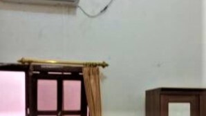 A room with a window, an air conditioning unit mounted on the wall, and a wooden cabinet. - Penginapan Meli (Surabaya)