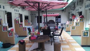 Un espace de jeux pour enfants avec une table ronde, des chaises et un parasol rose.