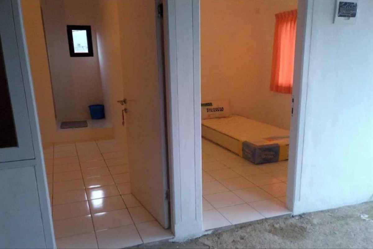Una habitación con una cama, un ventanal pequeño y una puerta.