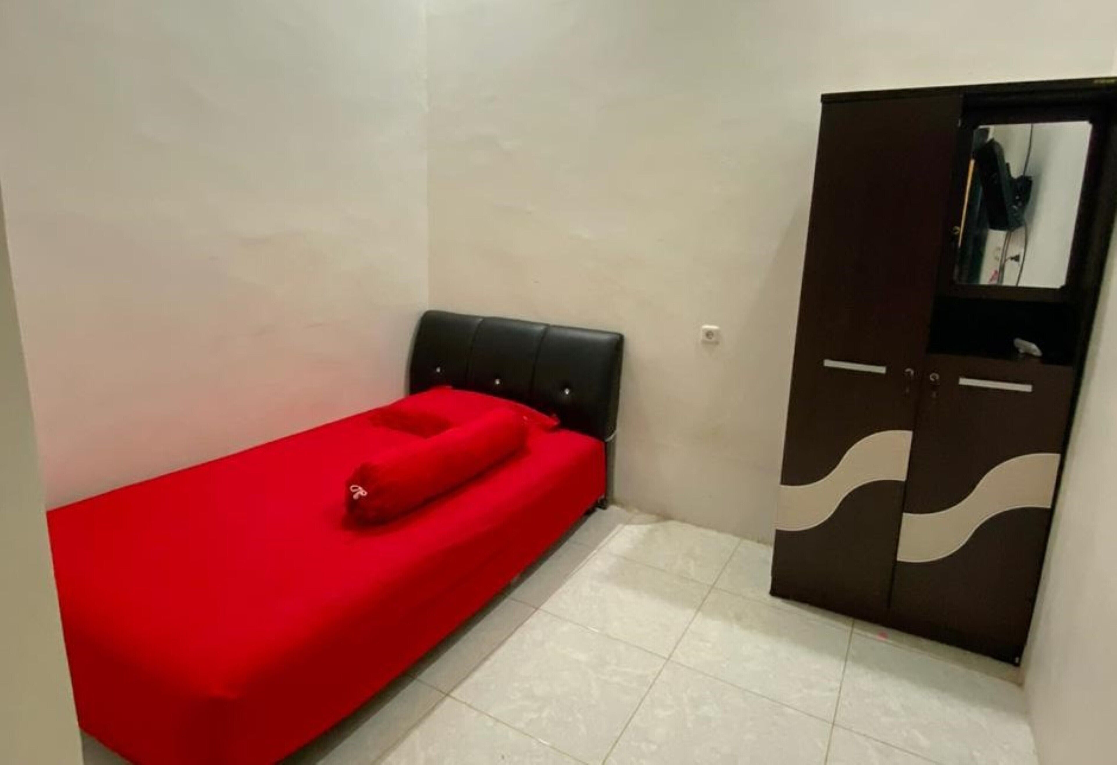 Una habitación pequeña con una cama individual, un armario y un espejo.