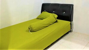 A single bed with a black headboard and green bedding. - Radja Guest House (Makassar)