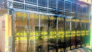 A metal gate with yellow accents and a barred design. - Radja Guest House (Makassar)