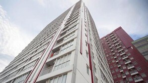 A tall, modern building with a white facade and red accents. It has multiple floors with balconies and large windows. - Apartment Taman Melati Surabaya by Havana Friends (Surabaya)