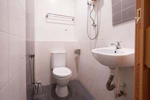 A small, clean bathroom with a toilet, a sink, and a shower. - Gurney Inn (George Town)