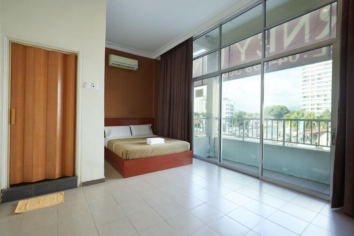 A hotel room with a large sliding glass door to the outside, a bed with a wooden headboard, and a small air conditioning unit on the wall.