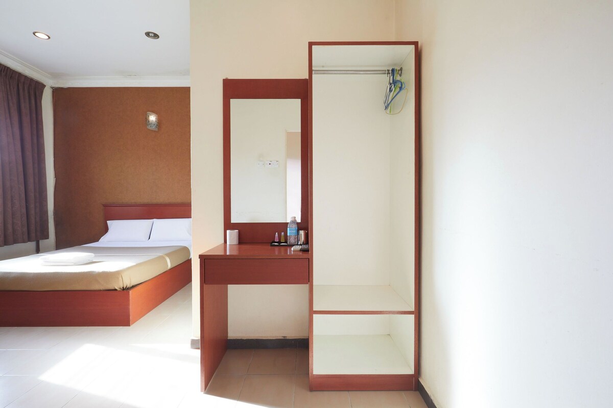 Camera d'albergo con un letto, una scrivania, uno specchio e un angolo doccia.