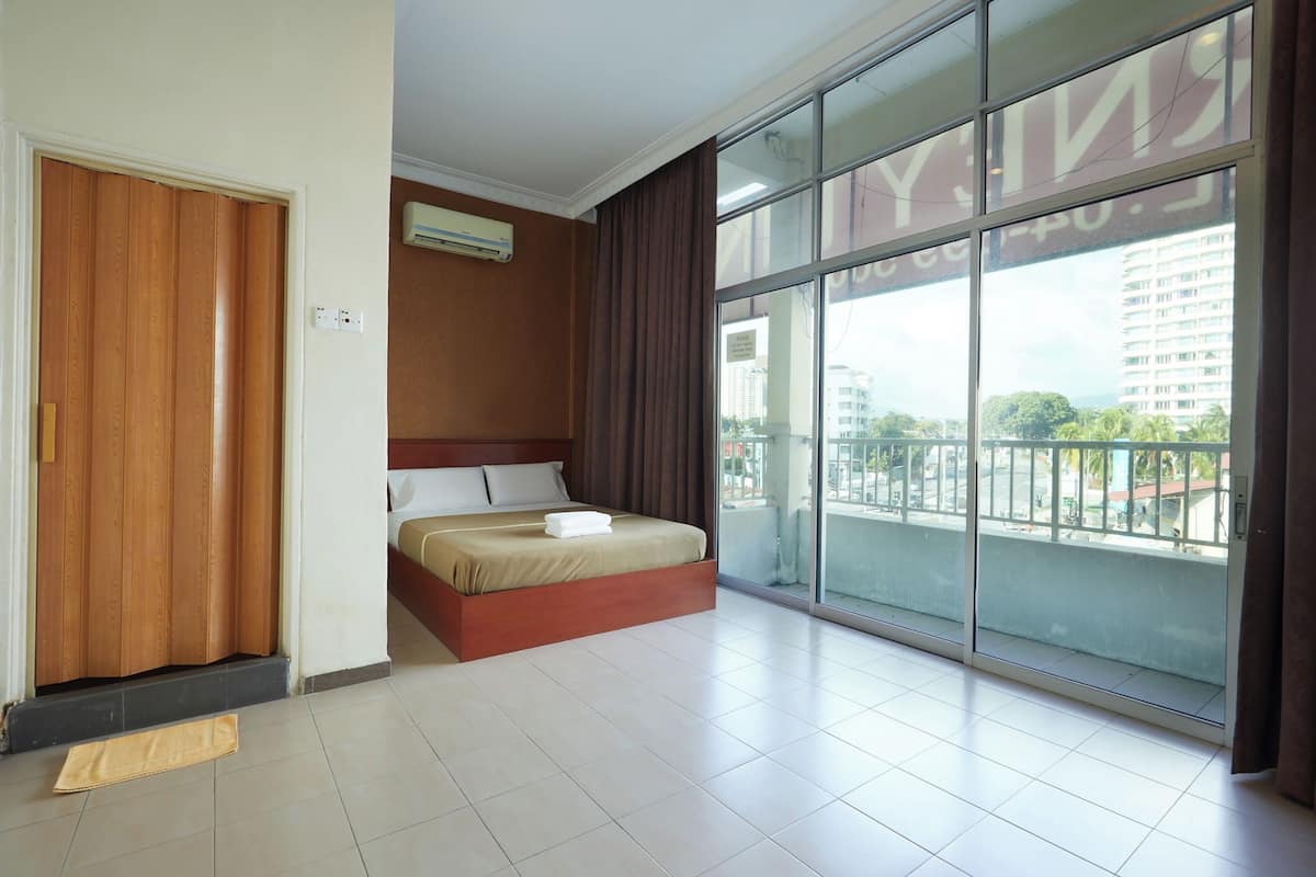 A hotel room with a large sliding glass door to the outside, a bed with a wooden headboard, and a small air conditioning unit on the wall.