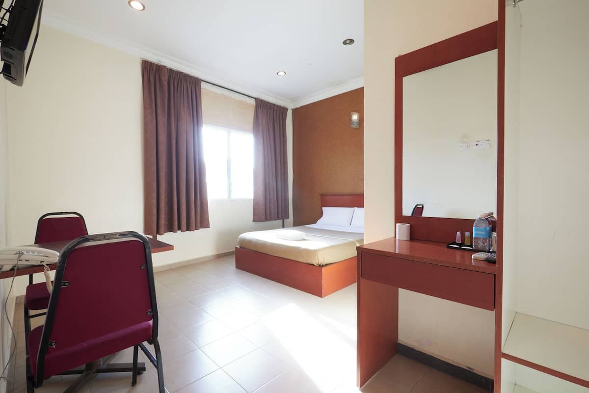 A hotel room with a bed, a desk with a chair, a small table, and a mirror.
