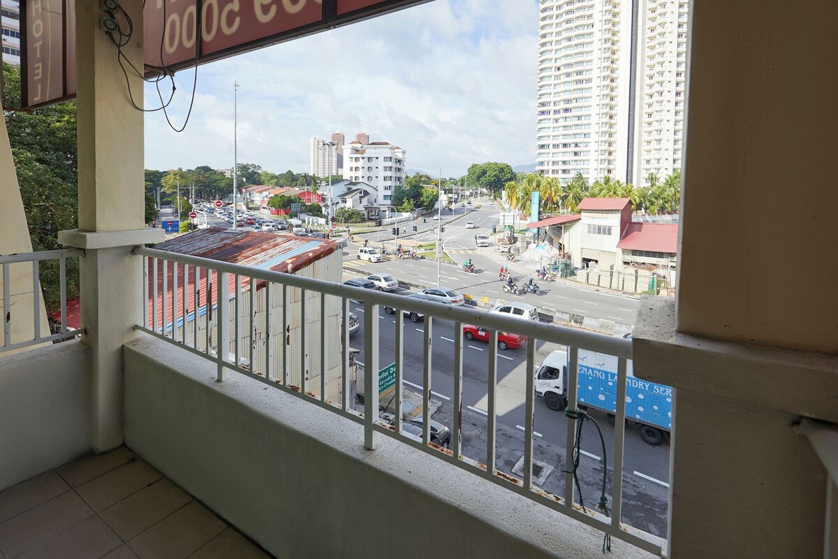 Un balcone con vista su una strada trafficata, edifici e un cartello per una lavanderia.