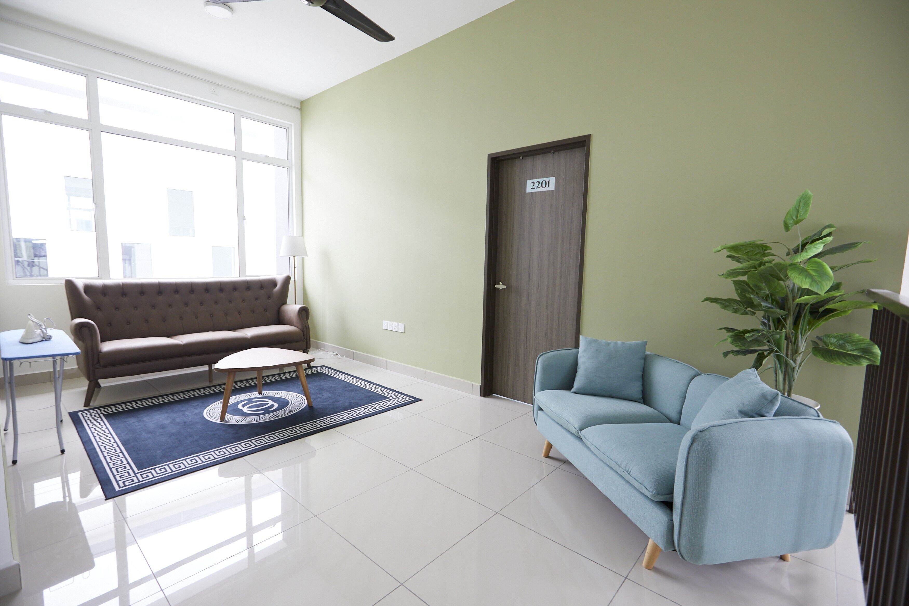 A living room with a brown sofa, a blue sofa, a small table, and a large window.