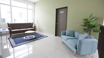 A living room with a brown sofa, a blue sofa, a small table, and a large window.