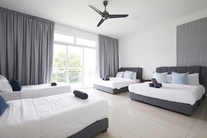 Ein modernes Hotelzimmer mit drei Betten, einem Deckenventilator und großen Fenstern.