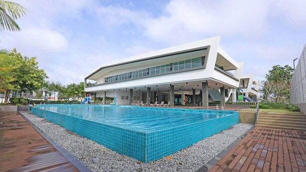 A modern building with a large rectangular swimming pool surrounded by pebbles and wooden decking. - Desaru Arcadia Villa By Convergence (Bandar Penawar)