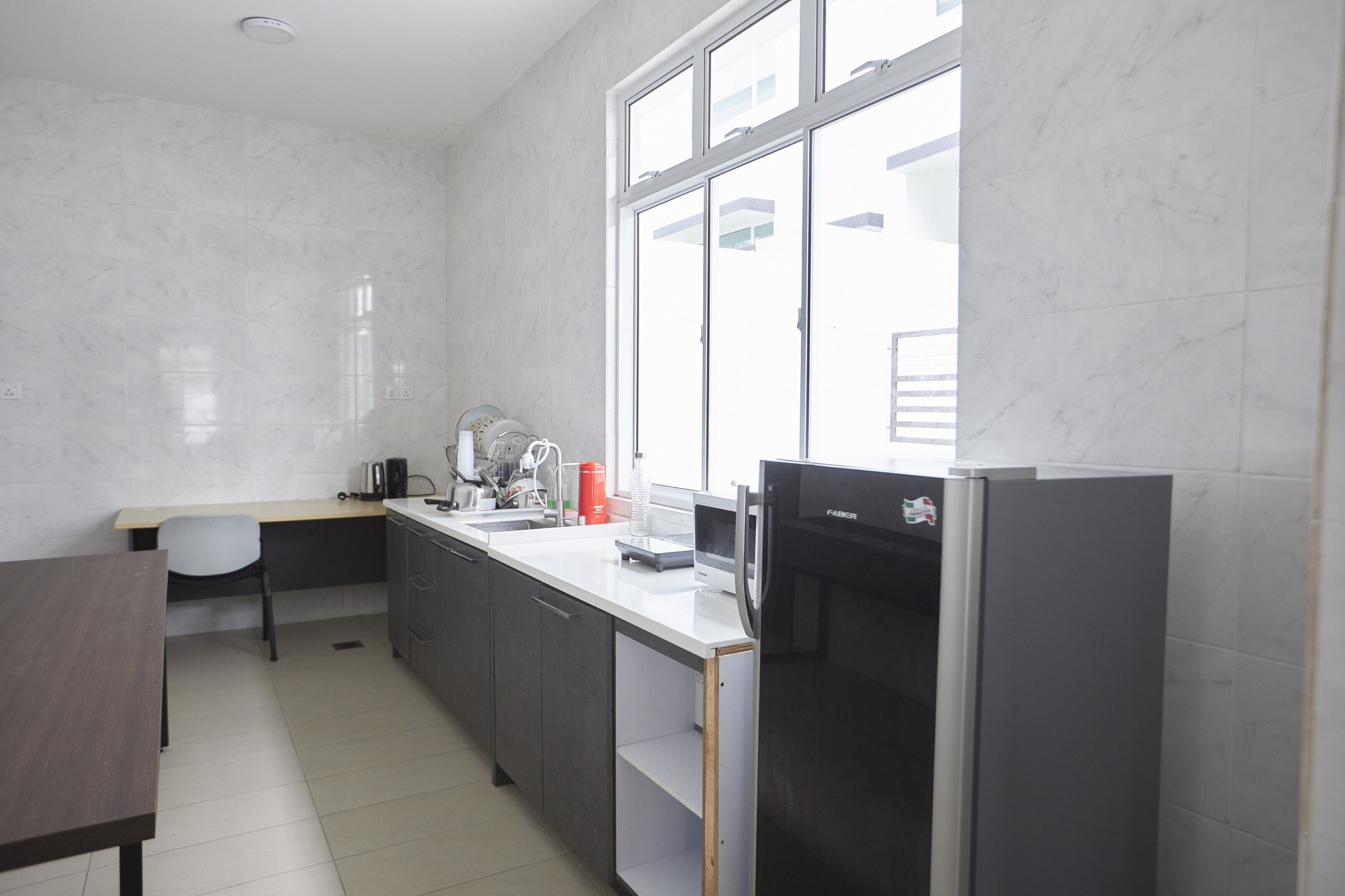 Una cocina moderna con un refrigerador empotrado, un lavamanos y una ventana que proporciona luz natural.