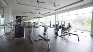 A gym with various exercise equipment, large windows, and ceiling fans. - Desaru Arcadia Villa By Convergence (Bandar Penawar)