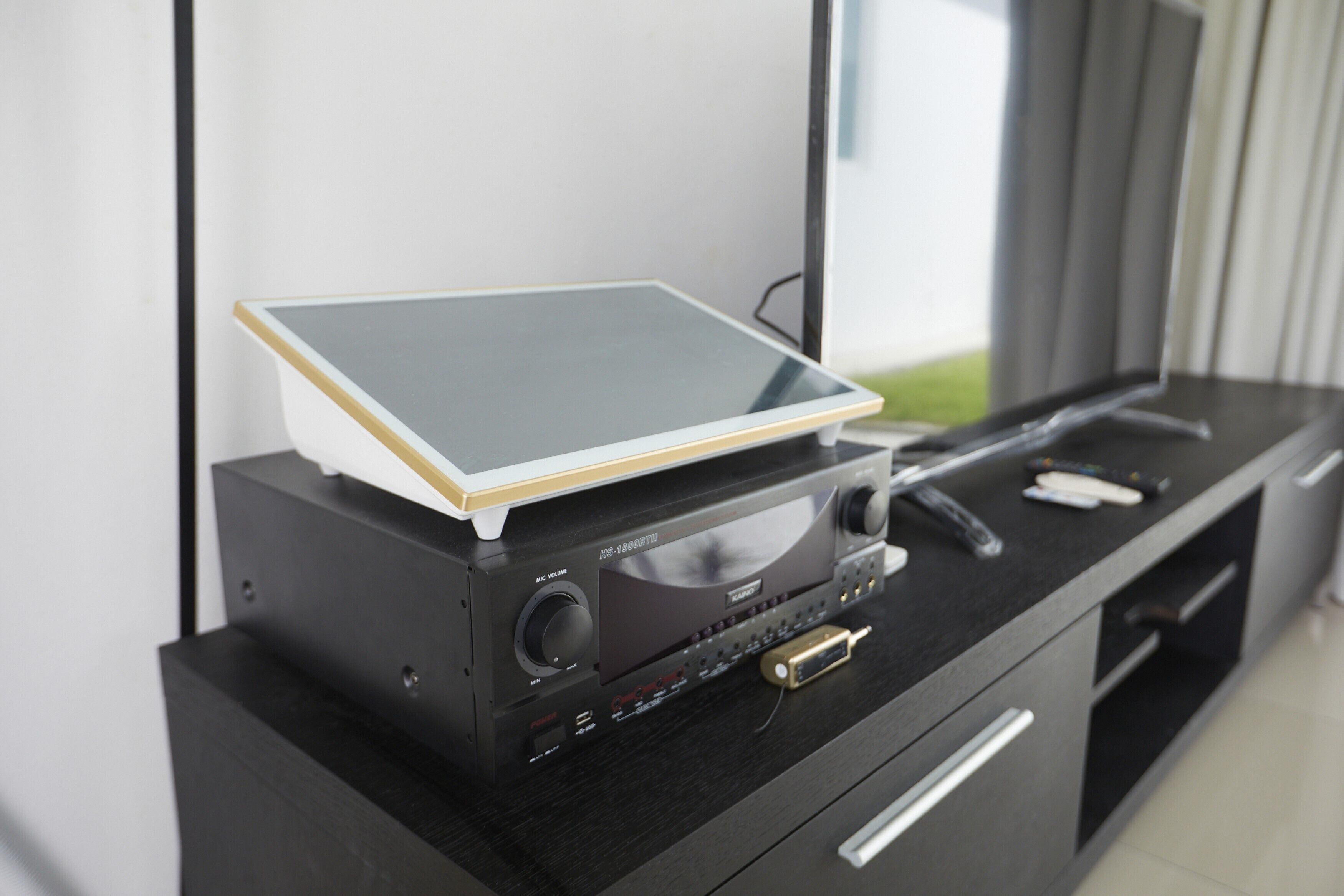 Un mueble de entretenimiento moderno con una tableta, un sistema de sonido y un televisor de pantalla plana.