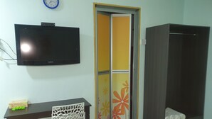Habitació amb televisió de pantalla plana, escriptori amb cadira, armari i porta amb un disseny floral.