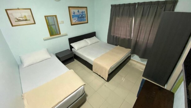 Habitació d'hotel amb dos llits, una petita taula de nit, aire condicionat fixat a la paret i dos quadres emmarcats.