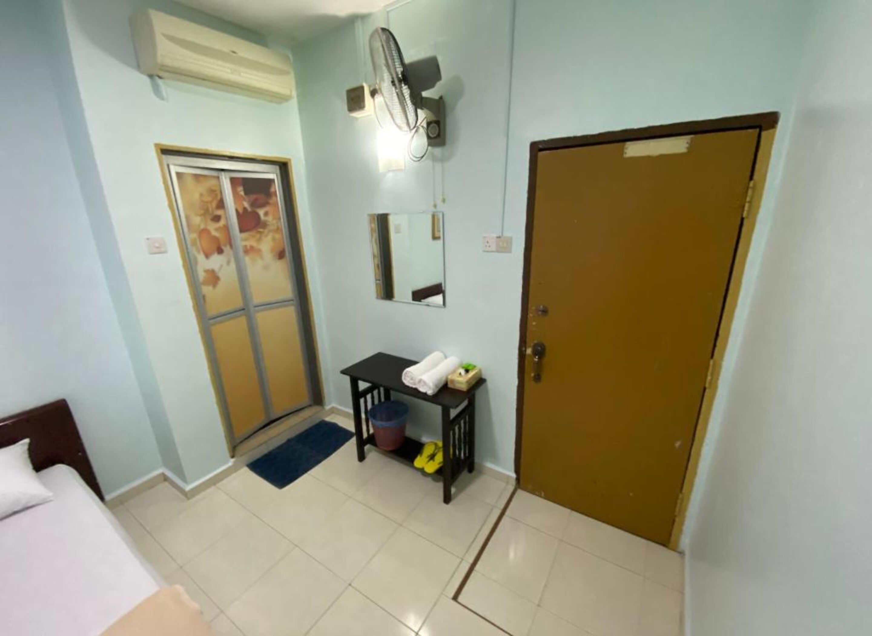 A hotel room with a bed, a desk, a chair, a door, and a window.