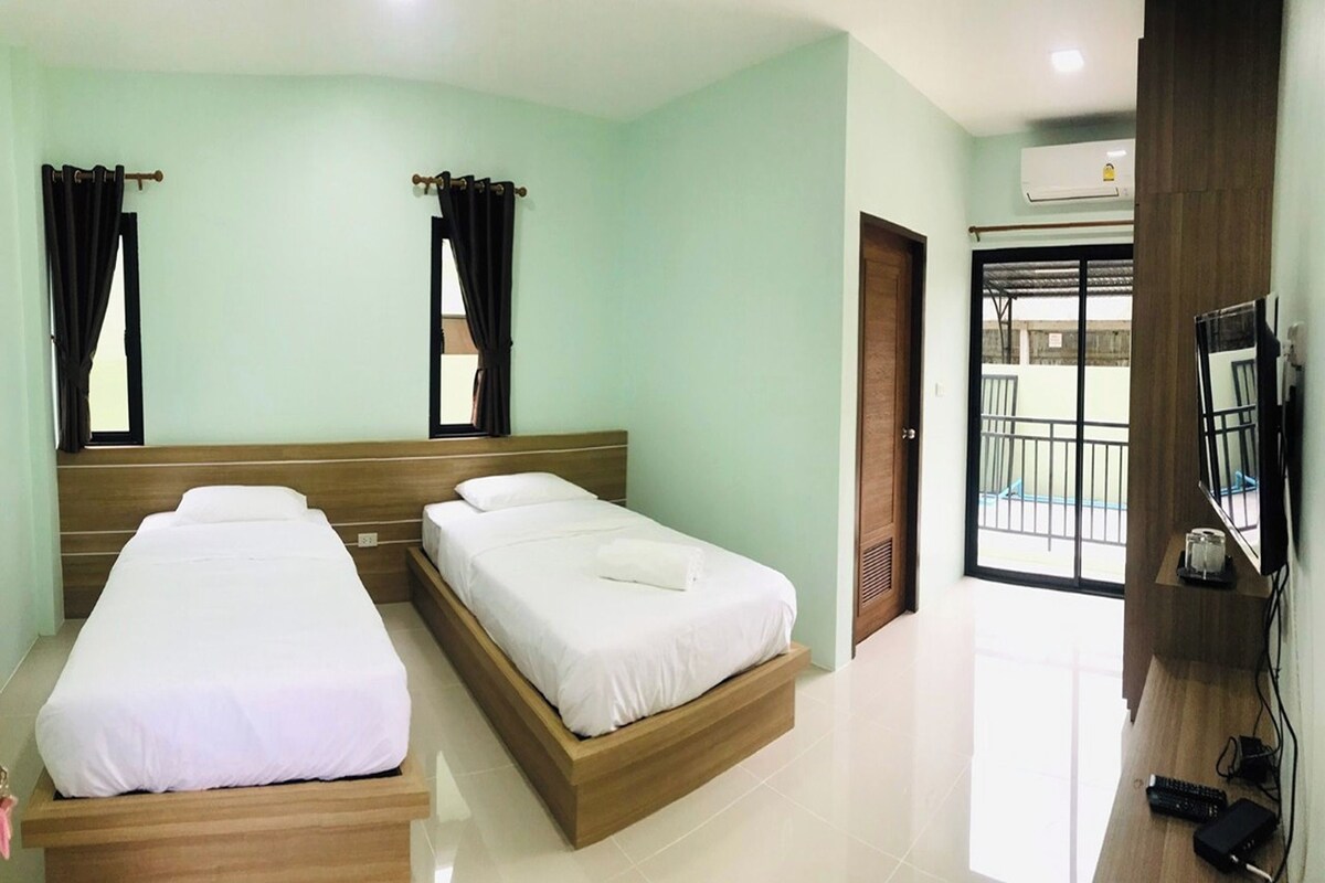 A hotel room with two beds, a TV, and a balcony.