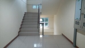 Una escalera conduce a un piso superior con vistas a árboles a través de una ventana.