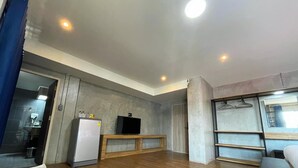 A modern kitchen with a refrigerator, a TV, and wooden cabinets. - Rabbit Hotel Phimai (Phimai)