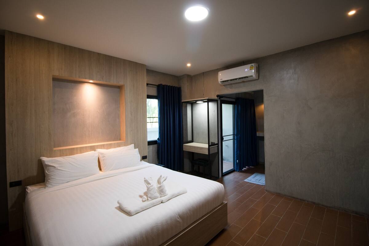 Una habitación de hotel moderna con una cama grande, un escritorio y un vestidor.