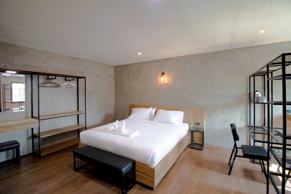 Una habitación de hotel moderna con una cama de madera, un banco, un escritorio y una silla.