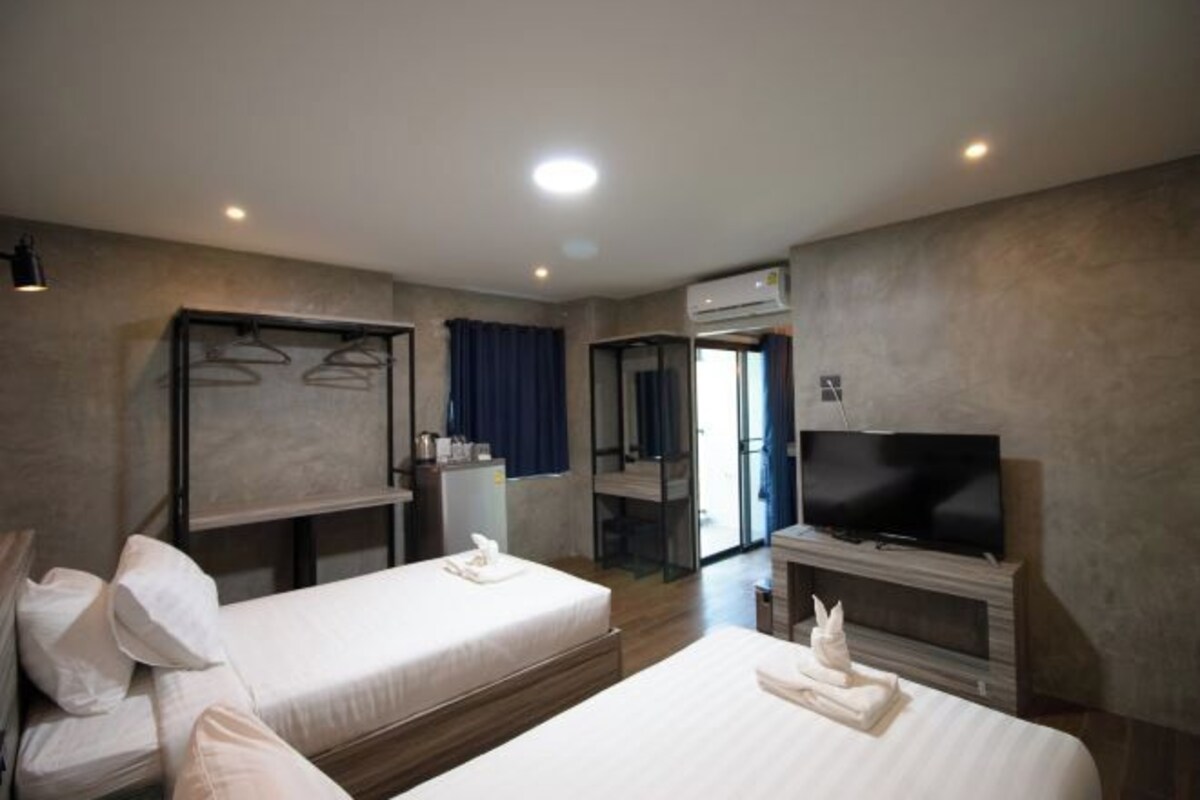 Habitación de hotel con dos camas, televisión, armario y aire acondicionado.