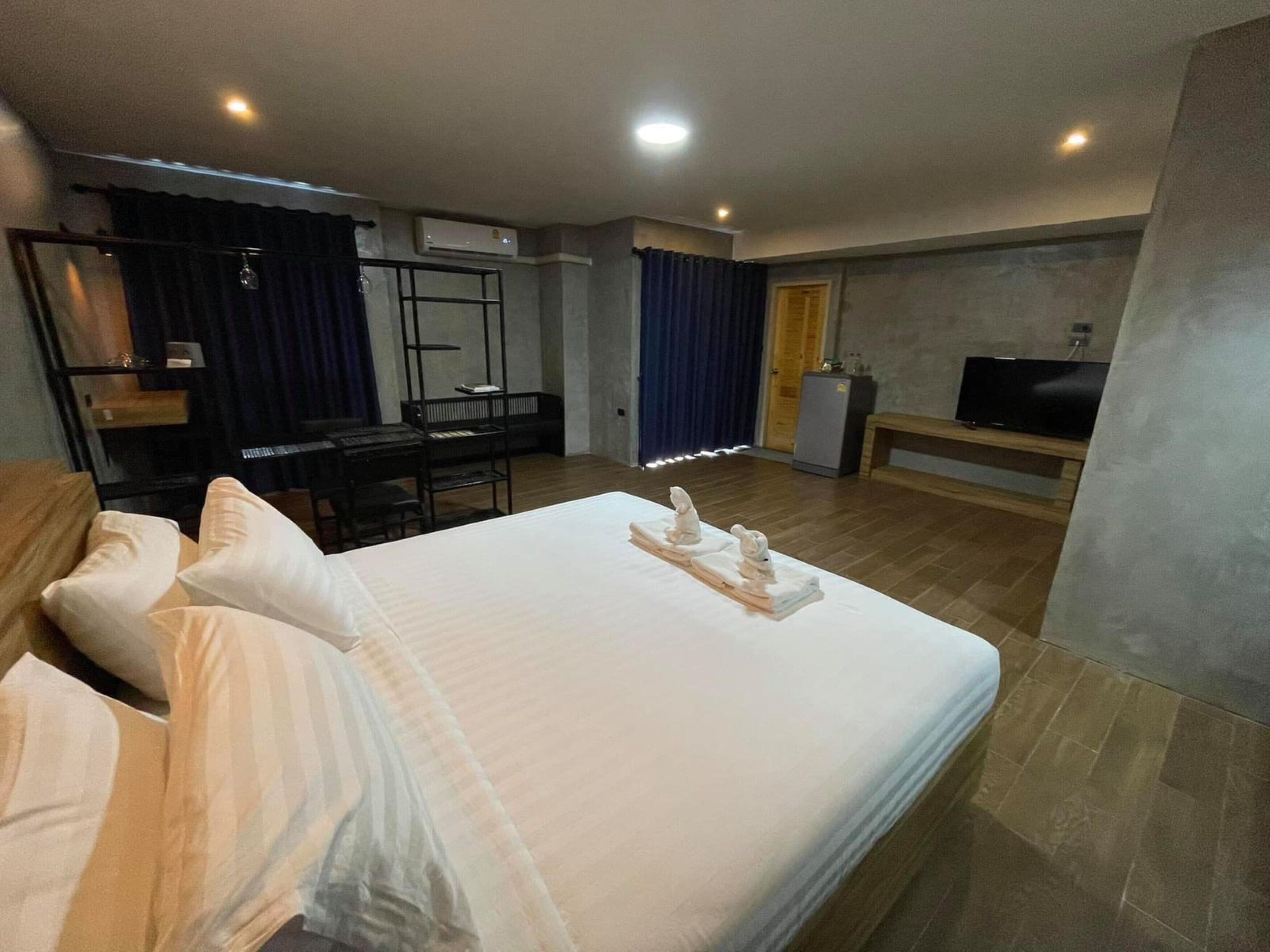 A hotel room with a bed, a desk, a chair, a television, and a minibar.