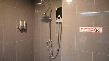 Zona de ducha con ducha de mano, cabezal de ducha portátil y grifo empotrado en la pared. Hay un cartel con un círculo rojo y una línea que indica prohibido secarse con toallas.