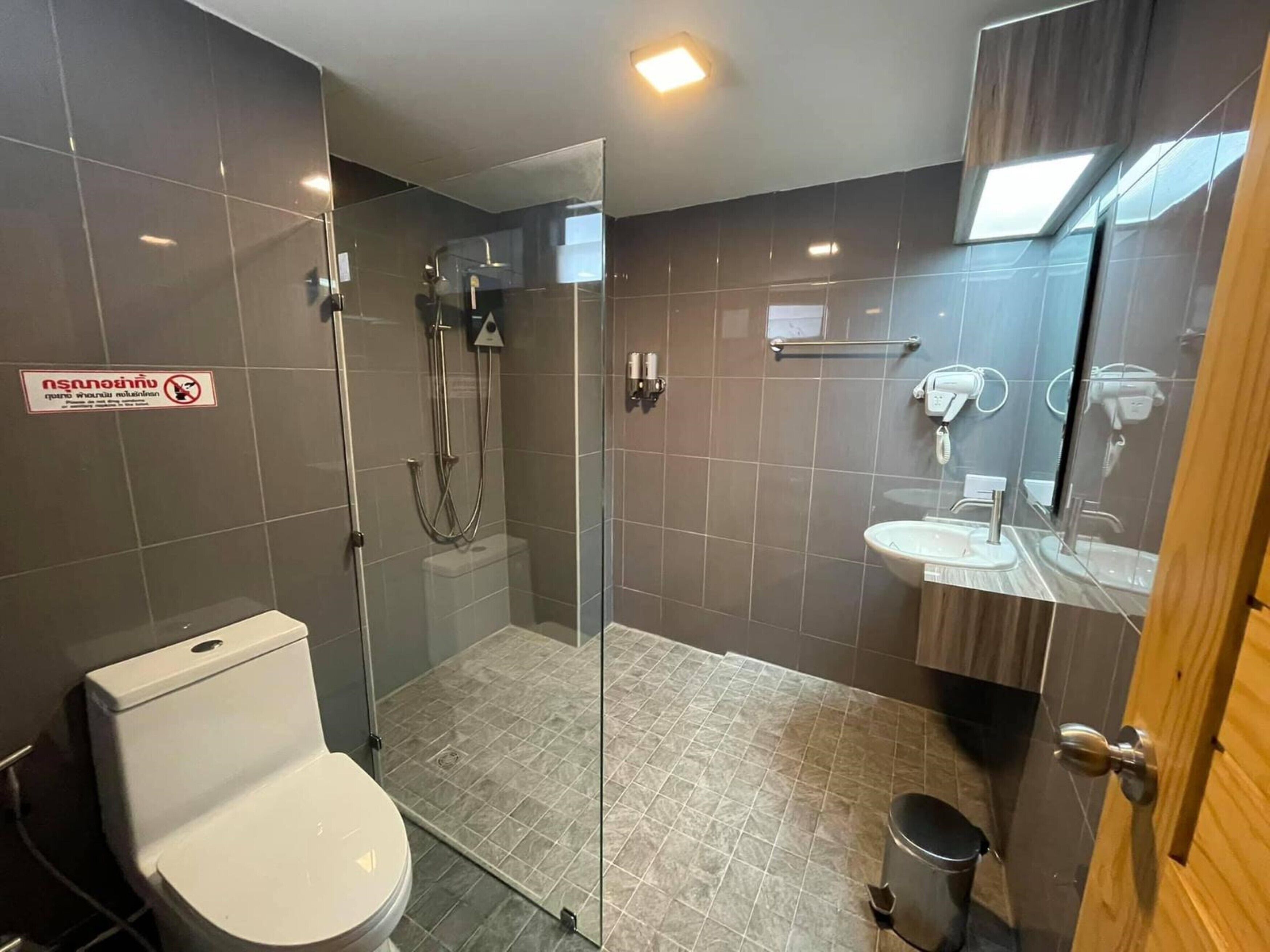 A modern bathroom with a glass-enclosed shower, a toilet, a sink, and a mirror.