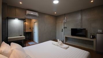 A hotel room with a bed, a TV, a minibar, and a desk with a chair.
