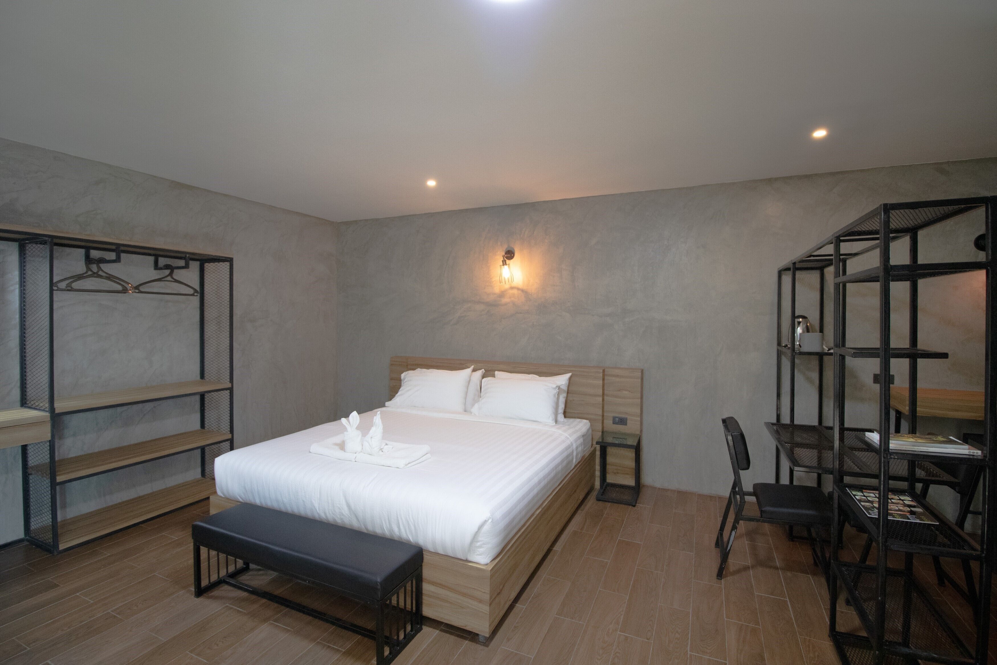 A modern bedroom with a large bed, bedside tables, a desk, and shelving units.