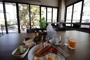 Una mesa de desayuno con diversos alimentos, como huevos, tocino y tostadas, junto con salsas y bebidas.