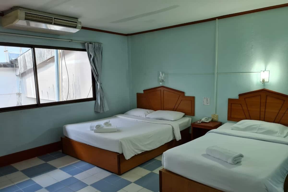 Une chambre d’hôtel avec deux lits, une fenêtre avec des rideaux, un climatiseur fixé au mur et un sol carrelé.