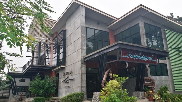 A modern building with a balcony, large windows, and a sign indicating a restaurant. - Saney Apartment (Pak Chong)