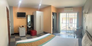 A hotel room with a bed, a small refrigerator, a TV, a wardrobe, and a balcony with a table and chairs. - Nasa Hotel (Wichit)