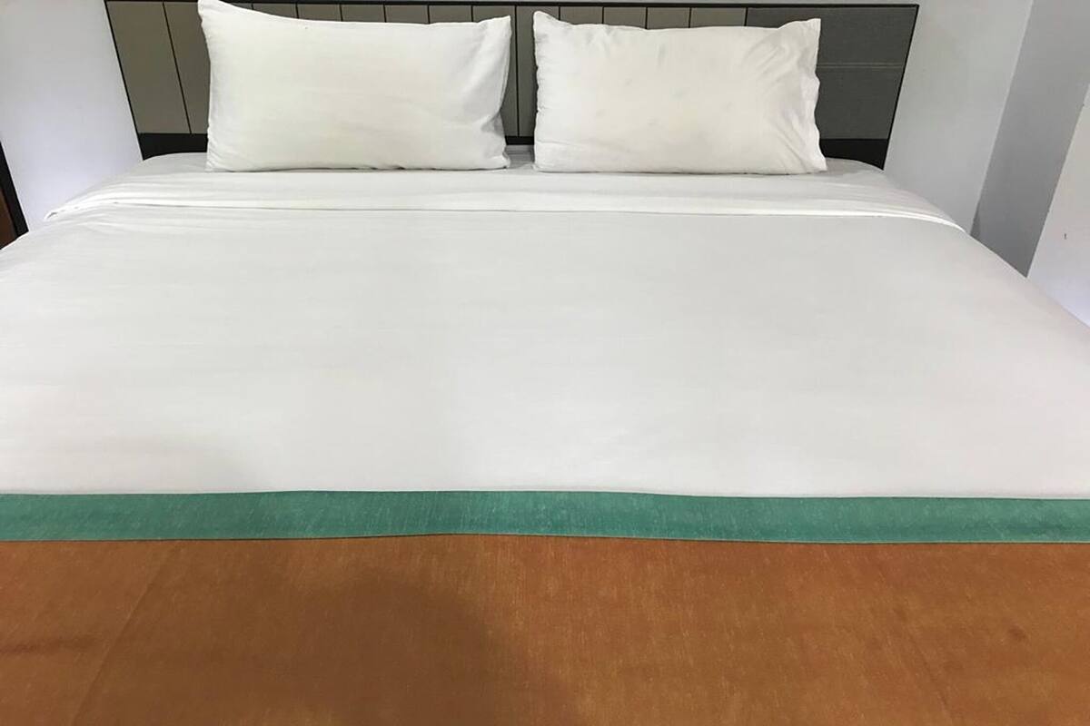 A bed with white bedding and a green accent at the foot.