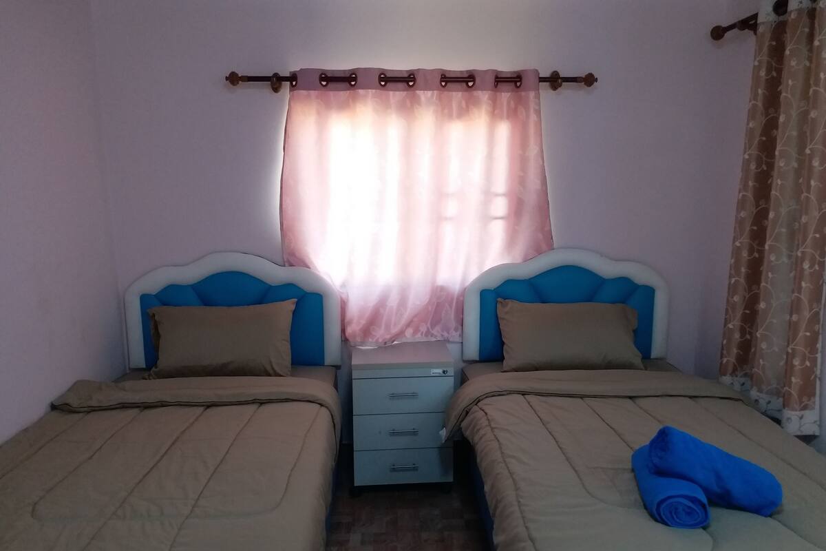 Une chambre avec deux lits, une table de chevet et une fenêtre avec des rideaux.
