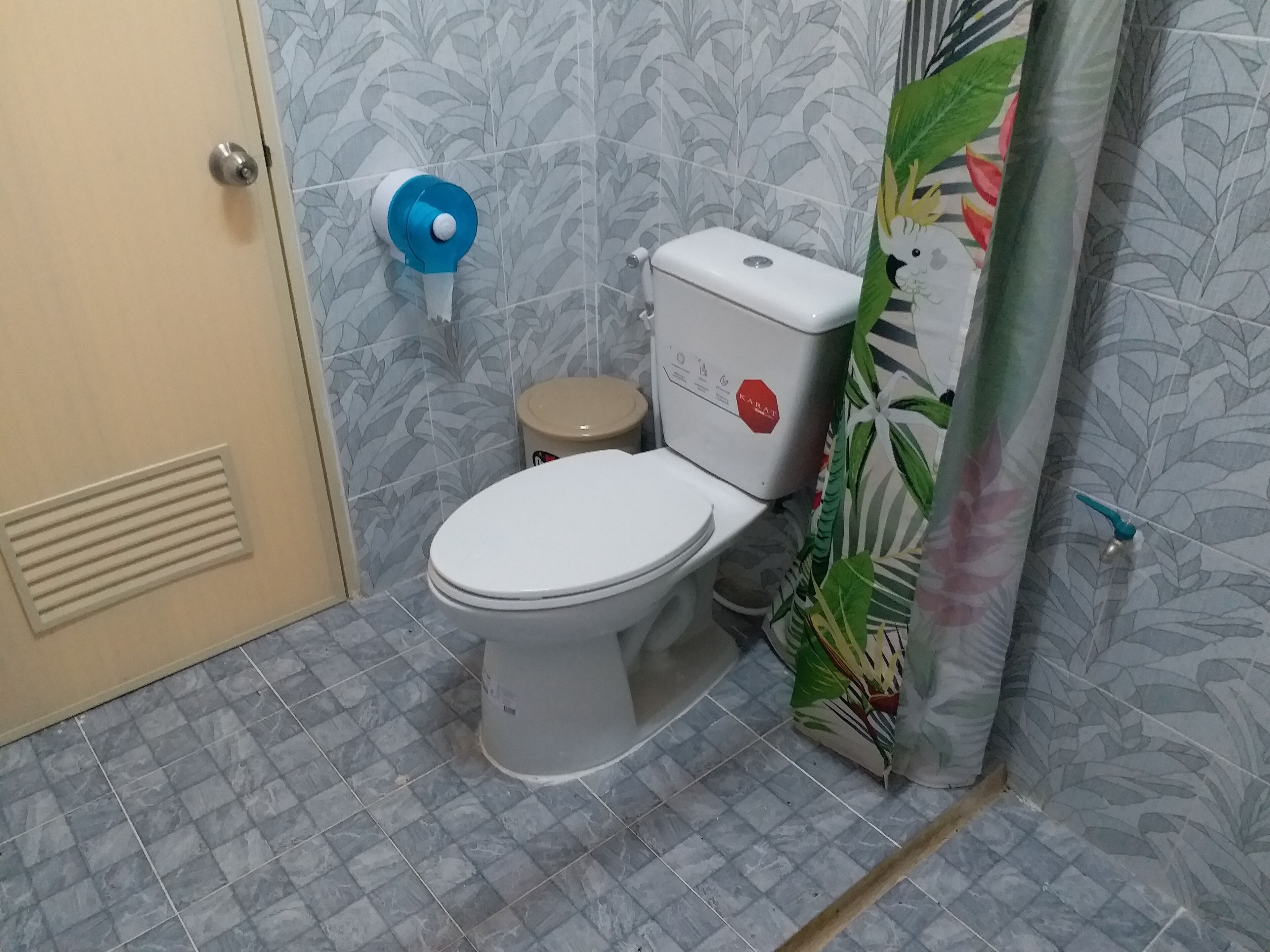 Un baño con inodoro, secador de manos y soporte para papel higiénico.
