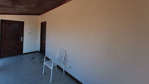 A room with a wooden ceiling, a white wall, and a metal chair. - Lek Homestay (Si Racha)