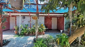 A covered outdoor area with potted plants, a seating area, and a door. - Lek Homestay (Si Racha)