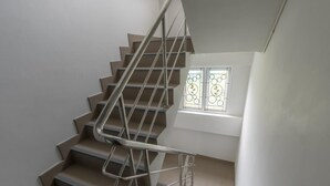 A modern staircase with metal railings and a small window with decorative glass. - MiddleWay House (Bangkok)